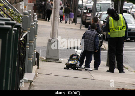 Les enfants de l'école attendant pour traverser la rue à côté d'un brigadier scolaire à Jersey City, NJ, USA Banque D'Images