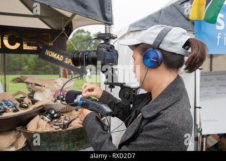 9 Mar 2019, une journaliste portant des écouteurs enregistre à la fois vision et son à la Festival Africultures Wyatt Park, Brunehaut, Sydney, Australie. Banque D'Images