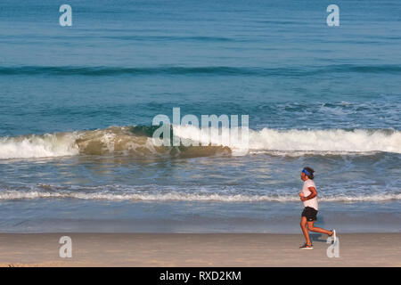 Sur un matin tôt à Bang Tao Beach, Phuket, Thailand, un jogger s'étend le long de la rive Banque D'Images