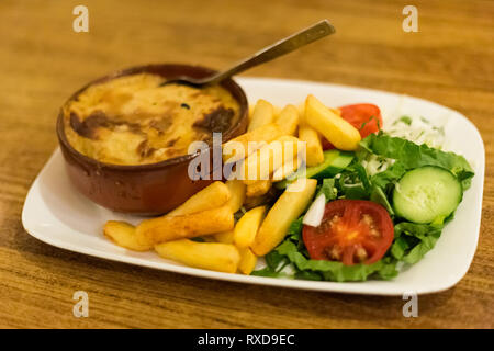 La Moussaka avec salade et frites dans un restaurant local à Larnaca. Nourriture chypriote traditionnel sur l'île de Chypre. Banque D'Images