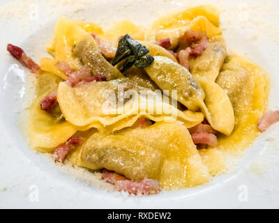 Cuisine italienne - dans le style Casoncelli alla bergamasque (pâtes farcies de chapelure, l'oeuf, le parmesan, le boeuf haché, salami) dans un bol blanc close up Banque D'Images