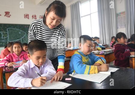 Ruili, province chinoise du Yunnan. Mar 8, 2019. Un professeur donne des conseils à une étudiante birmane à l'école primaire de Yinjing Yinjing Village de Ruili, sud-ouest de la province chinoise du Yunnan, le 8 mars 2019. L'école primaire Yinjing est située à la frontière de la Chine et le Myanmar et il dispose d'un total de 135 étudiants, dont 36 étudiants du Myanmar. Credit : Qin Qing/Xinhua/Alamy Live News Banque D'Images