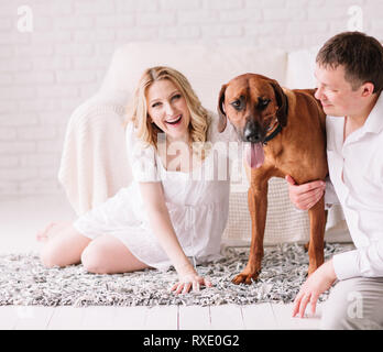 Jeune famille avec leur chien assis sur le lit dans la chambre à coucher Banque D'Images