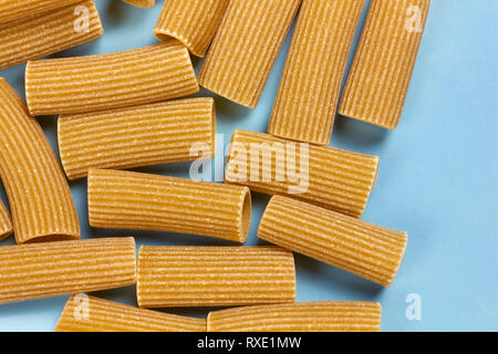 Rigatoni de grains entiers cuits sur un fond bleu Banque D'Images