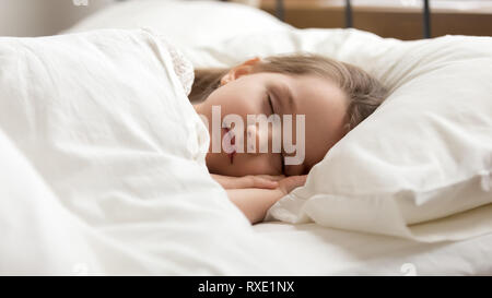 Calme kid girl sleeping in bed couverts de duvet chaud Banque D'Images