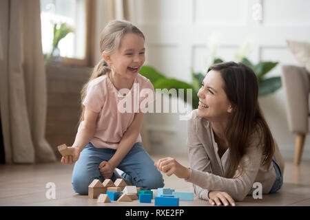 Heureuse maman et enfant fille rire en jouant avec des blocs en bois Banque D'Images