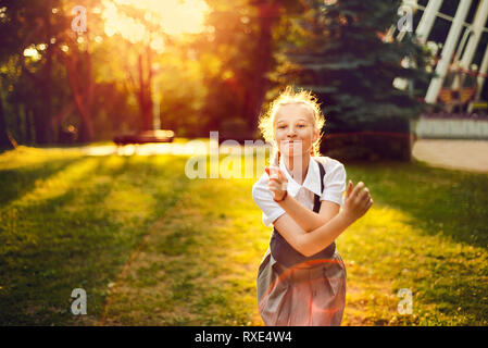 Enfant de sexe féminin à l'élastique, de la danse et s'amuser dans le parc, au coucher du soleil Banque D'Images