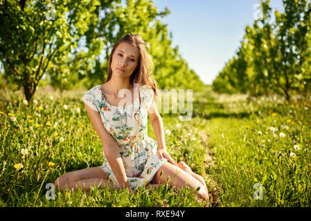 Un modèle féminin posant dans un verger à couper le souffle en été. Banque D'Images