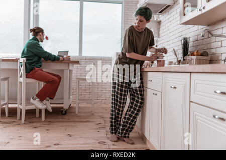Petite amie wearing pajamas se cacher de l'homme et de l'alcool ? Banque D'Images