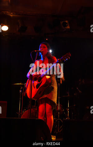 Chanteuse avec son jeu de guitare acoustique sur scène Banque D'Images