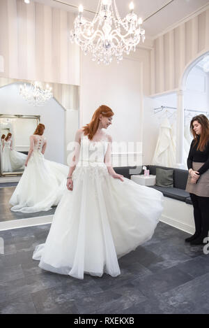 Pretty caucasian girl essayer sur des robes de mariée boutique dans un quartier chic. Banque D'Images