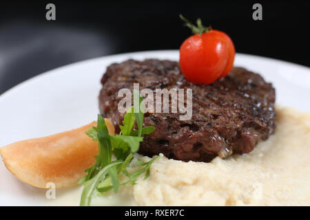 Escalope de viande frits sur une assiette, avec purée de céleri, garnie de cerises tomates et pommes aigres, isolée pour un menu Banque D'Images