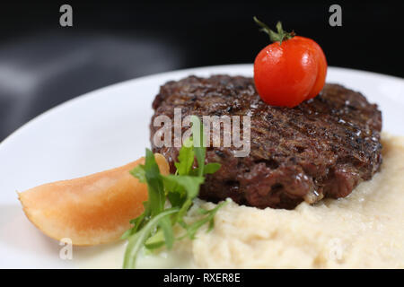 Escalope de viande frits sur une assiette, avec purée de céleri, garnie de cerises tomates et pommes aigres, isolée pour un menu Banque D'Images