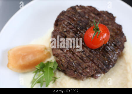 Escalope de viande frits sur une assiette, avec purée de céleri, garnie de cerises tomates et pommes aigres, isolée pour un menu Banque D'Images