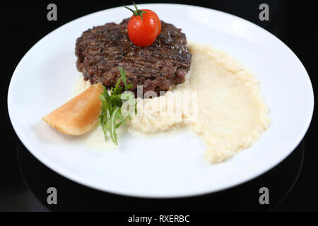 Escalope de viande frits sur une assiette, avec purée de céleri, garnie de cerises tomates et pommes aigres, isolée pour un menu Banque D'Images