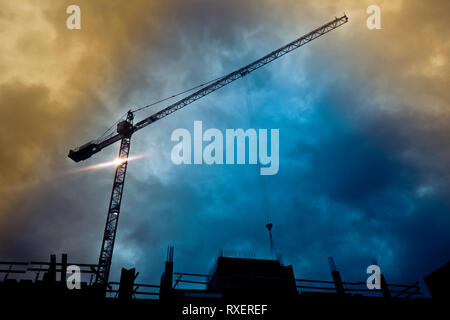 Grue a tour en silhouette sur un site de construction Banque D'Images