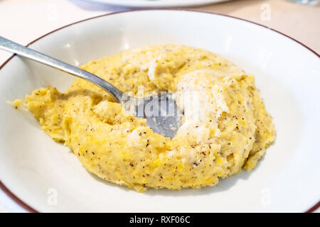 Cuisine italienne - portion de polenta Taragna (porridge à partir d'un mélange de maïs et de farine de sarrasin avec du beurre et fromage) sur plaque blanche dans les reste Banque D'Images