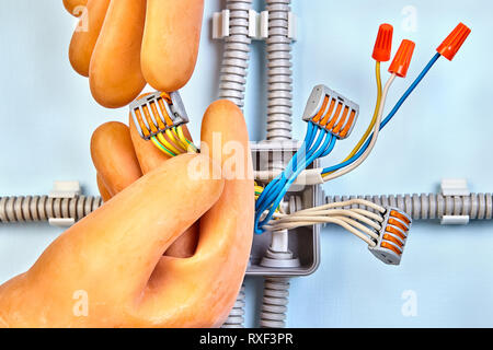 Electricien dans le caoutchouc des gants de sécurité fait de nouveau la boîte de jonction électrique compact avec connecteur 5 fils avec leviers. Banque D'Images