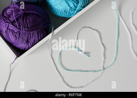 La technique de fils de laines à tricoter colorées comme cœur de la conception des symboles sur le tableau blanc. Se concentrer sur les boules de fils. Banque D'Images