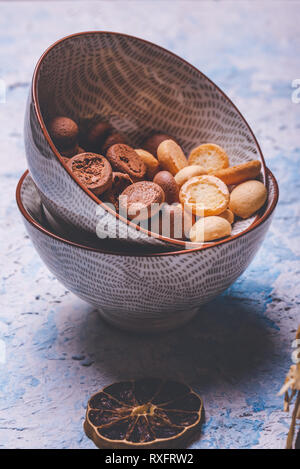 Photo verticale avec plusieurs petits biscuits éponge. Les biscuits sont la lumière et l'obscurité avec le cacao. Les sucreries sont dans deux bols en céramique placés sur carte avec lumière Banque D'Images