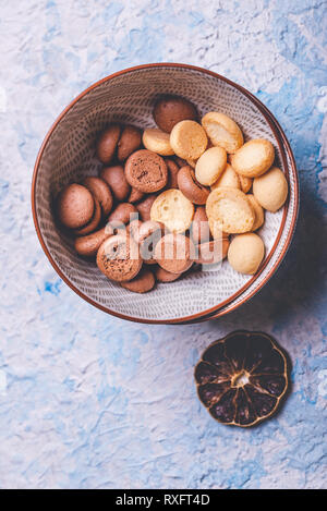 Photo verticale avec vue de dessus sur plusieurs petits biscuits éponge. Les biscuits sont la lumière et l'obscurité avec le cacao. Les sucreries sont dans deux bols en céramique placés sur la lumière Banque D'Images