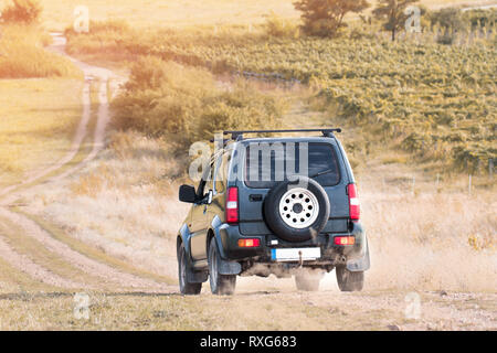 Voiture suv tout-terrain sur route en terre dans le coucher du soleil Banque D'Images