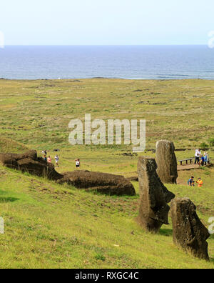 De nombreux visiteurs sur la pente de Volcan Rano Raraku rempli de statues Moai géant inachevé abandonné avec l'océan Pacifique en toile de fond, l'île de Pâques Banque D'Images