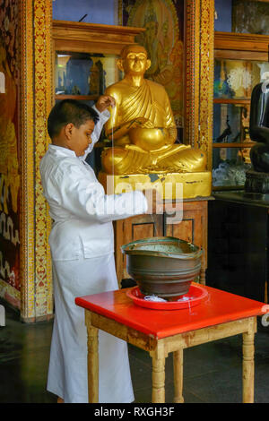 Un garçon se prépare à l'intérieur d'un temple à candlewick Colombo, Sri Lanka. Banque D'Images