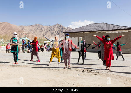 Murghab, le Tadjikistan, le 23 août 2018 : les filles et les jeunes femmes kirghizes pratiquent une danse sur l'aire d'une école à Mourgab. Contre les forts Banque D'Images