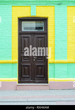 Vieille porte en bois brun vert toxiques sur mur de briques. Ancienne porte sur la façade d'un immeuble dans une rue étroite. Arrière-plan de voyage Banque D'Images