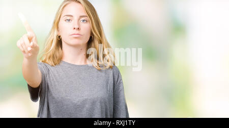 Belle jeune femme portant des T-shirt oversize sur fond isolé avec le doigt pointant vers le haut et l'expression de colère Banque D'Images