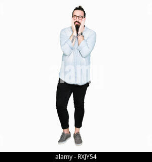 Jeune homme hipster avec de longs cheveux et barbe portant des lunettes assez mains couvrant le visage, la dépression et la tristesse, contrarié et irrité pour problème Banque D'Images