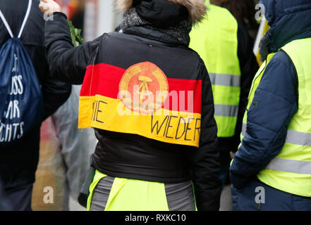 Landau, Allemagne. 9 mars 2019. Un manifestant porte un drapeau de l'ex-RDA sur ses épaules avec 'plus jamais' écrit dessus. Autour de 80 personnes de organisations d'extrême droite ont protesté dans la ville de Landau dans le Palatinat contre le gouvernement allemand et les migrants. Ils ont également adopté le jaune de la veste jaune Français Crédit : mouvement de protestation pacifique presse/Alamy Live News Banque D'Images