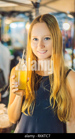 Femme à boire le jus de canne à sucre sur le marché asiatique pour le format vertical mobile Instagram histoire ou d'histoires. Fond d'écran mobile Banque D'Images