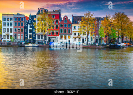 Situation touristique et de voyage spectaculaire, une ville avec des maisons traditionnelles néerlandaises. Canal de l'eau avec péniches au coucher du soleil, Amsterdam, Nethe Banque D'Images