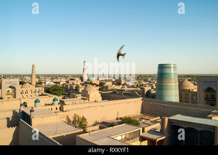 Des oiseaux volent au-dessus de la ville de Khiva au coucher du soleil. Fondée au 6ème siècle, Khiva est une belle ville préservée dans entre le Kyzylkum et deser Karakoum Banque D'Images