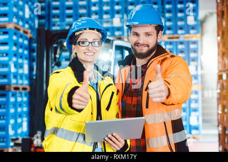 Les travailleurs de centre logistique showing thumbs-up Banque D'Images