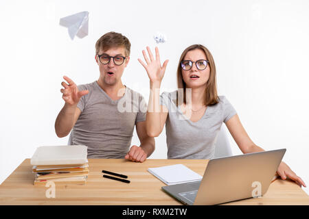 Espiègle, naughty étudiants avec grands verres throwing paper airplanes et papier froissé assis à la table. Banque D'Images