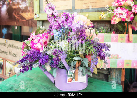 Décorée avec une table mauve arrosoir remplis de fleurs artificielles dans toutes sortes de nuances de violet. quelque part dans la ville de Frech Antibes Banque D'Images