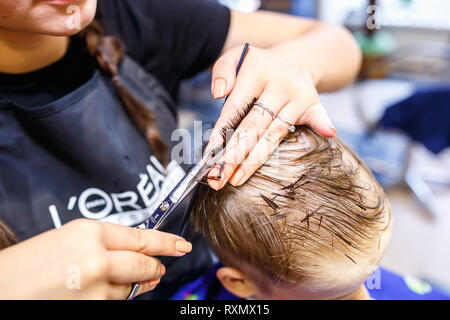 Minsk, Belarus - Mai 2016 : master coiffure coiffeur faisant une coiffure en salon de coiffure pour petit garçon adolescent Banque D'Images