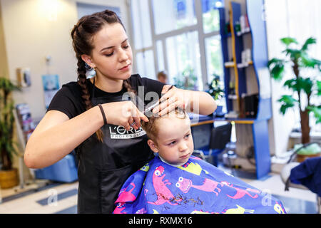 Minsk, Belarus - Mai 2016 : master coiffure coiffeur faisant une coiffure en salon de coiffure pour petit garçon adolescent Banque D'Images
