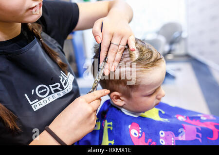 Minsk, Belarus - Mai 2016 : master coiffure coiffeur faisant une coiffure en salon de coiffure pour petit garçon adolescent Banque D'Images