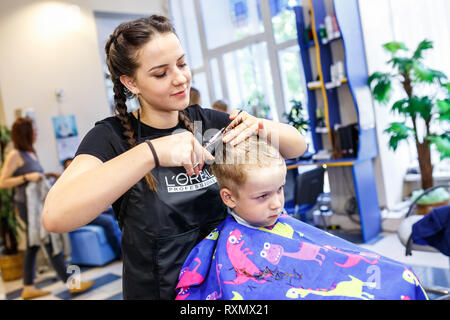 Minsk, Belarus - Mai 2016 : master coiffure coiffeur faisant une coiffure en salon de coiffure pour petit garçon adolescent Banque D'Images