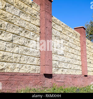 Clôture faite de briques et de plâtre décoratif. Clôture jaune rouge avec éléments. L'escrime de haut et beau. Banque D'Images
