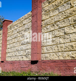 Clôture faite de briques et de plâtre décoratif. Clôture jaune rouge avec éléments. L'escrime de haut et beau. Banque D'Images