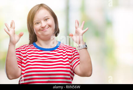 Les jeunes femmes adultes souffrant du syndrome de Down sur fond isolé smiling traversant les doigts avec l'espoir et les yeux fermés. Chance et concept superstitieux. Banque D'Images