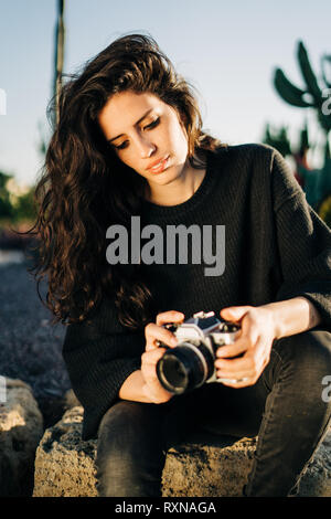 Portrait d'une jolie jeune femme avec un appareil photo rétro dans un parc durant le coucher du soleil Banque D'Images