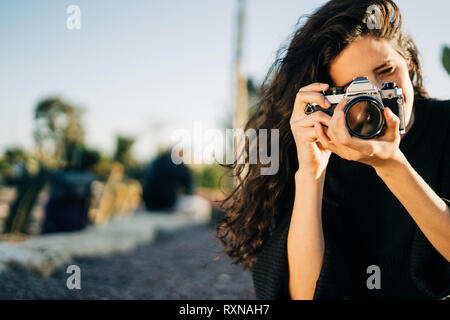 Portrait d'une jolie jeune femme avec un appareil photo rétro dans un parc durant le coucher du soleil Banque D'Images