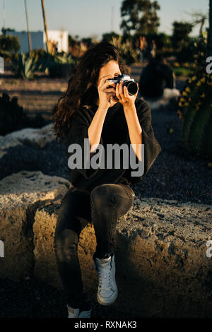 Portrait d'une jolie jeune femme avec un appareil photo rétro dans un parc durant le coucher du soleil Banque D'Images