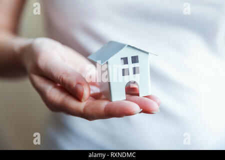 Female woman hands holding petit blanc miniature toy house. L'assurance des biens hypothécaires dream déménagement accueil concept et de l'immobilier Banque D'Images